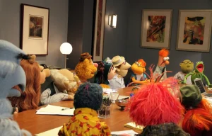 Muppets around a board table having a meeting